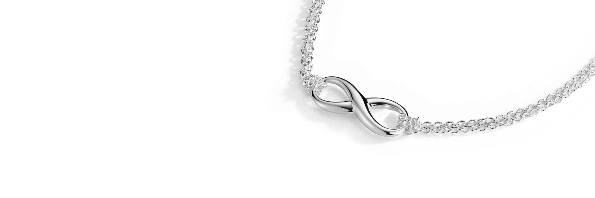 An infinity symbol hanging from a cable chain in sterling silver.